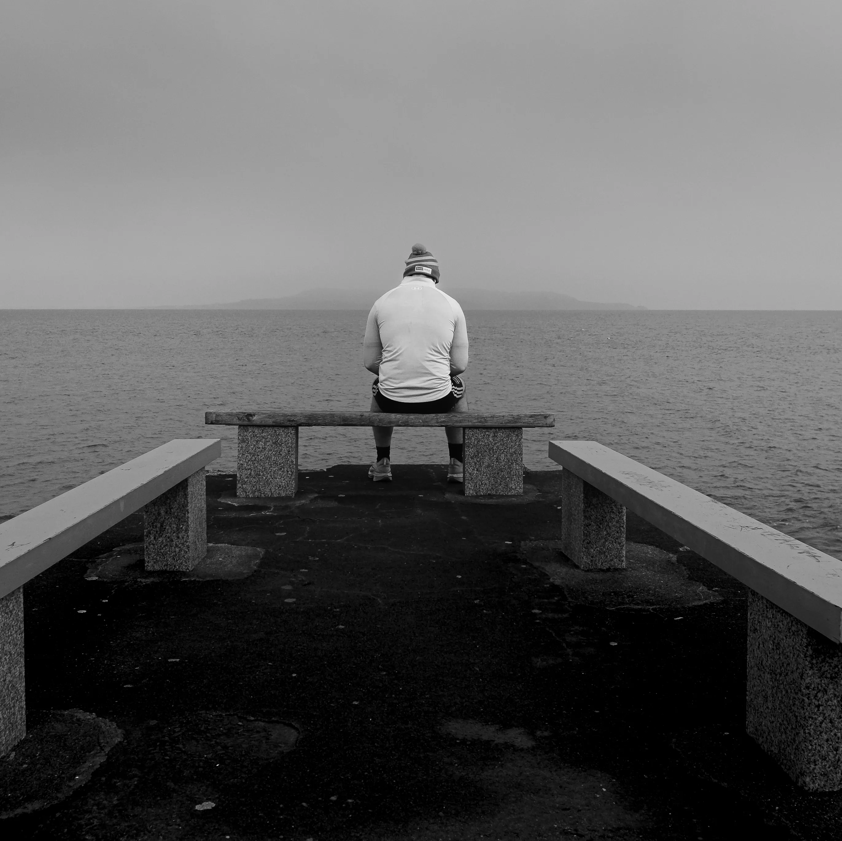 A man in a cold-weather running outfit looks out at the Howth peninsula from the Dun Laoghaire pier