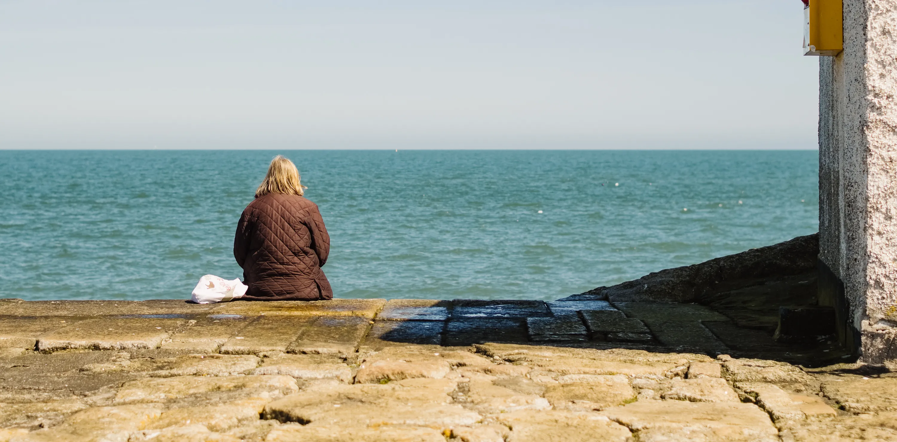 A woman eats her lunch while contemplating the ocean in Ireland