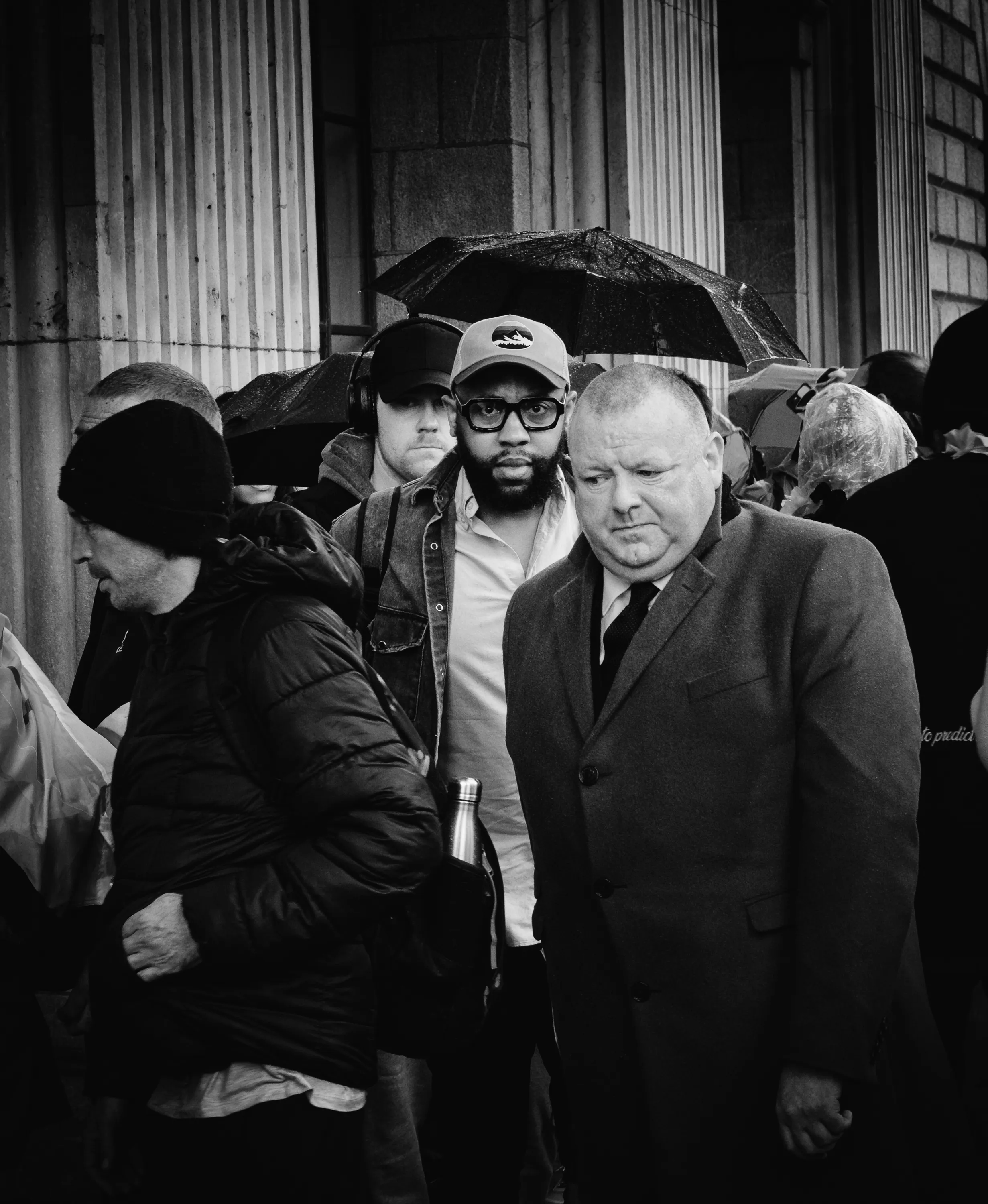 Two men navigate through a crowd while looking uncomfortable.