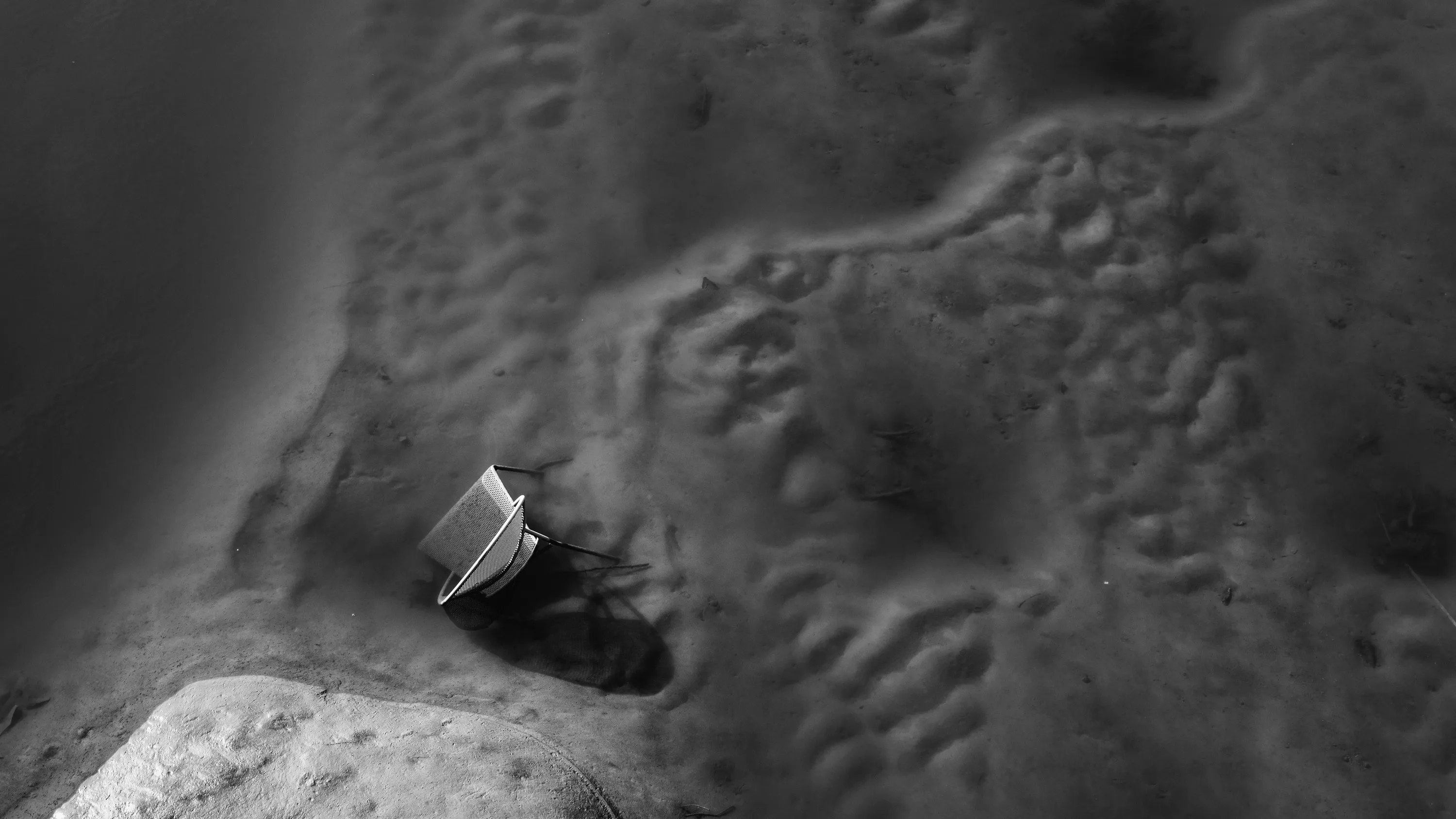 A metal chair can be seen half-buried in the riverbed at low tide