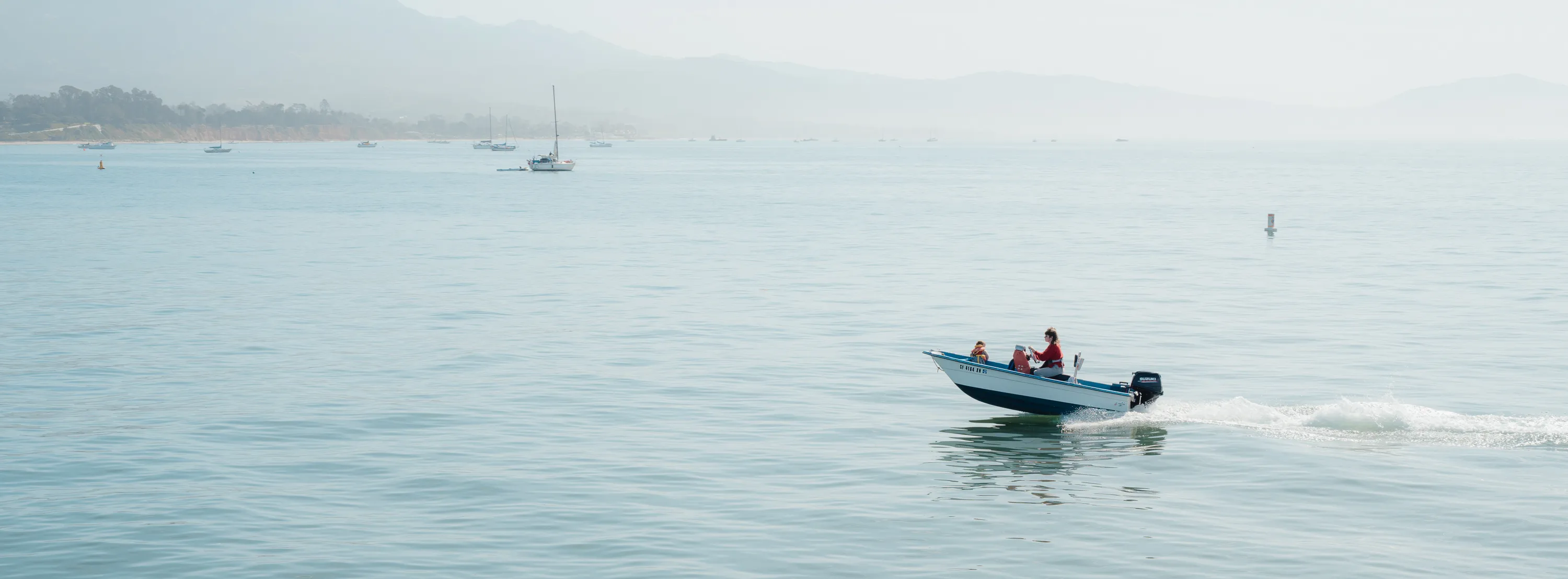 A shot from the Santa Barbara pier of people in a speedboat on a misty day